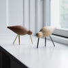 Two wooden bird figurines in light and dark brown with gold and black legs on a white surface.