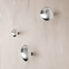 Set of three silver metallic wall hooks displaying a sleek, modern design on a light-colored background.