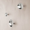 Set of three brushed silver wall hooks with smooth, rounded shapes against a soft, neutral background.