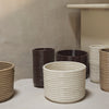 Set of textured ceramic baskets in beige, cream, brown, and dark brown, showcasing a ribbed pattern.