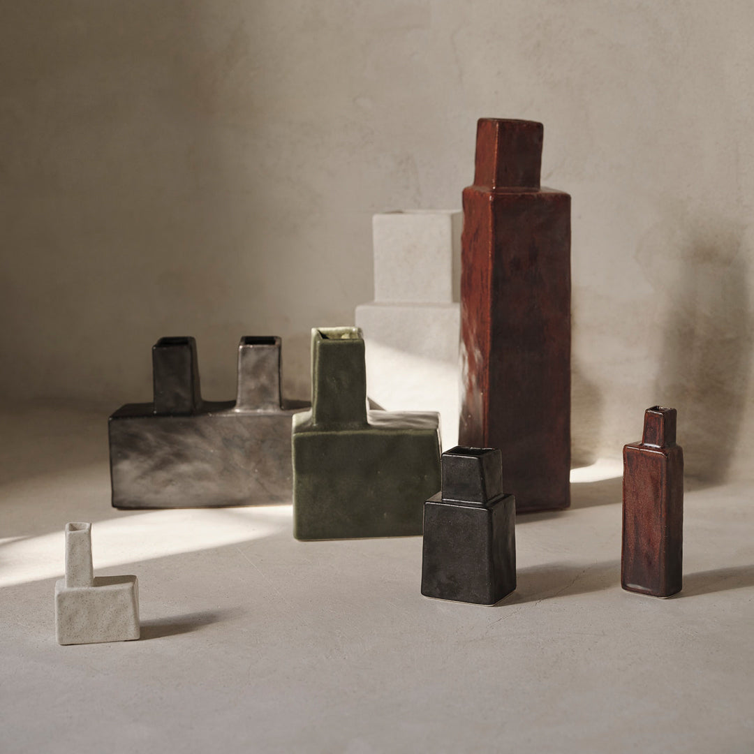 "Set of modern geometric vases in earthy tones: red, green, black, white, and gray, with textured finishes."