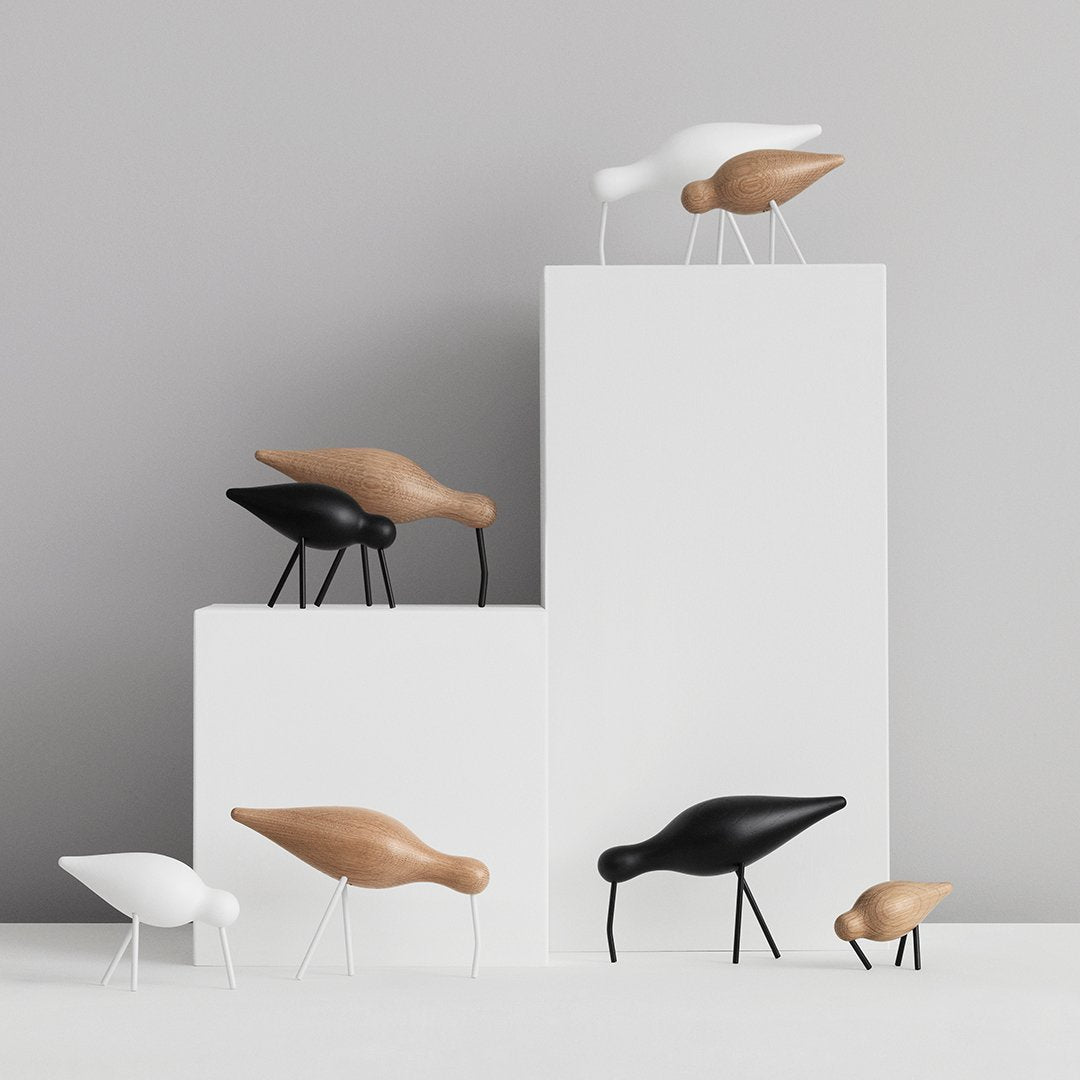 “Modern decorative birds in black, white, and natural wood colors on white pedestals, showcasing minimalist design.”