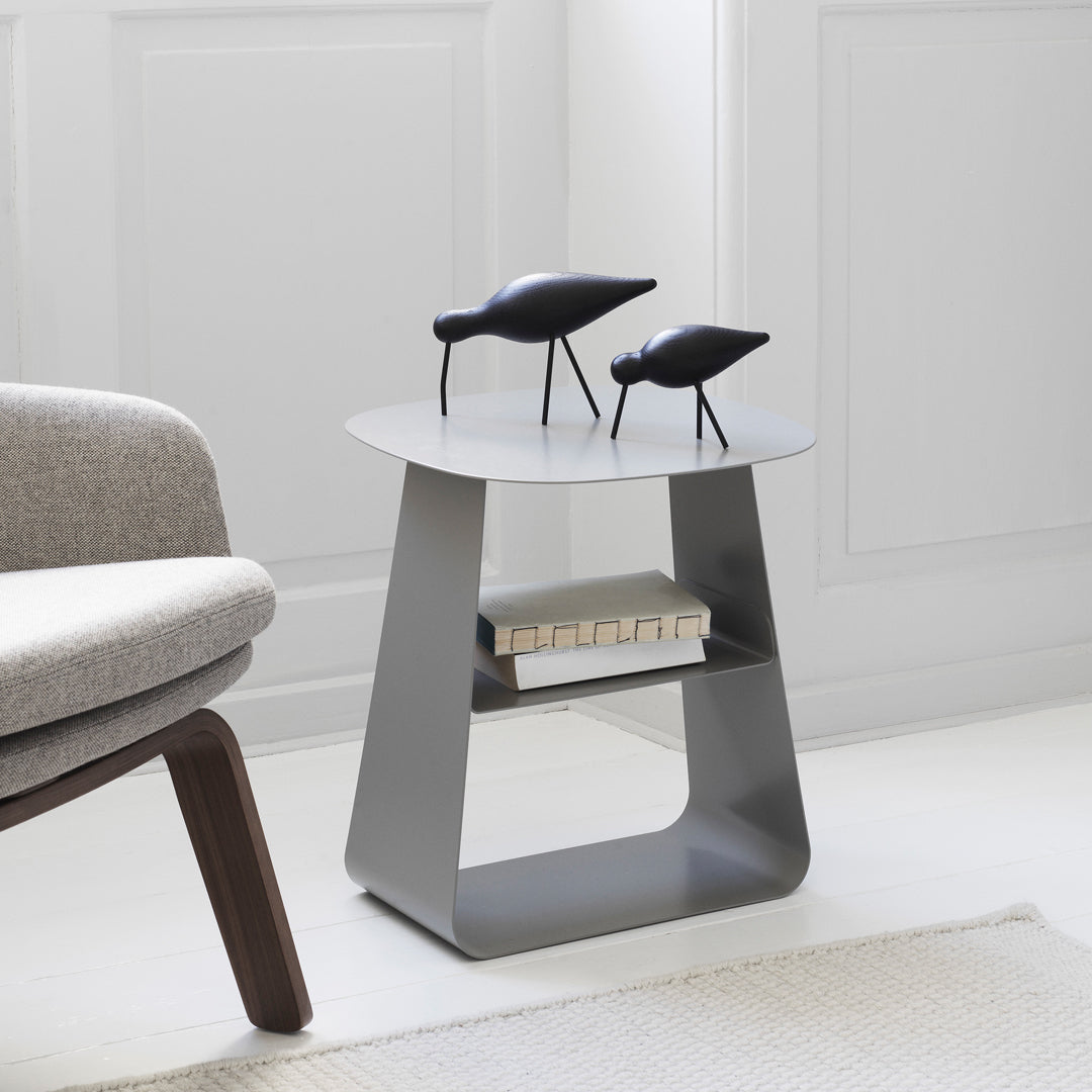 Stylish gray side table with a smooth round top and geometric design, featuring sleek black decor accents.
