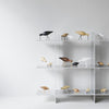 Assorted decorative bird figurines in black, white, and natural wood tones on a modern displayed shelf.