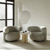 "Light gray, plush chairs with rounded designs, set against a neutral background and minimalist decor."