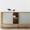 Light grey paneling with a ridged pattern on a wooden cabinet, complemented by black decorative birds.