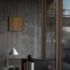 Modern interior featuring gray concrete walls, natural wood accents, and a sleek black and white furniture palette.