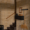 "Rustic brown brick wall, dark wooden accents, black storage unit, and a natural straw broom create a warm, modern look."