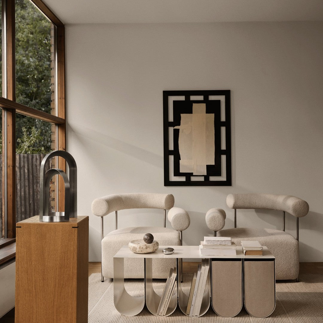 Beige and black patterned couch with round cushions; minimalist wall art in neutral tones, with wood and metal accents.
