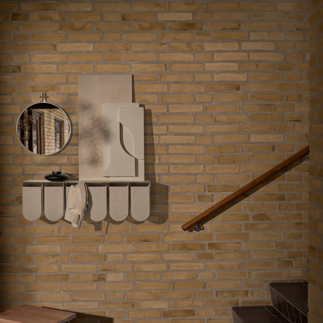 "Modern beige wall shelf with curved edges, round mirror, and minimalist design against textured brick background."