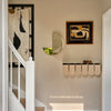 Abstract geometric patterns in neutral tones with a mix of black, cream, and gold accents in a modern hallway.