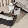 Stylish black and beige modern sofa with geometric white and gray side tables on a textured cream rug.