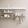 White wall-mounted shelves with minimalist glassware and ceramic dishes in neutral beige tones. Elegant and modern design.