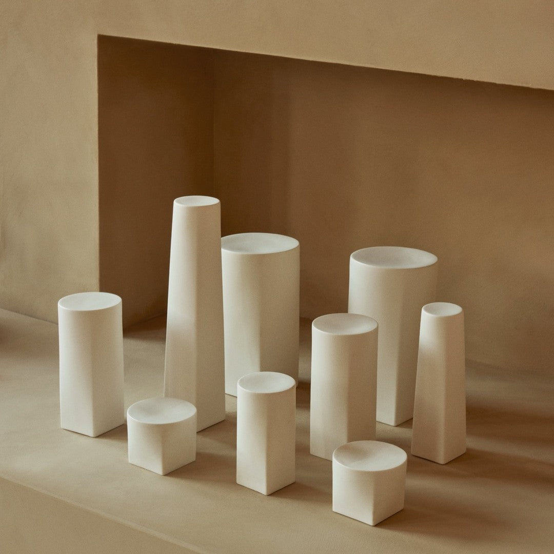 Minimalist white vases in various geometric shapes, arranged on a soft beige background. Perfect for modern decor.