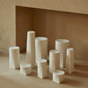 Neutral-toned geometric vases in various shapes and sizes, featuring smooth, matte finishes against a soft backdrop.