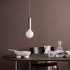 Modern pendant light with a matte white bulb and sleek gold metal accents against a rich brown backdrop.