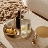 Elegant gold and clear glass drink set on a round tray, accented with lemon slices and a sleek ice bucket.