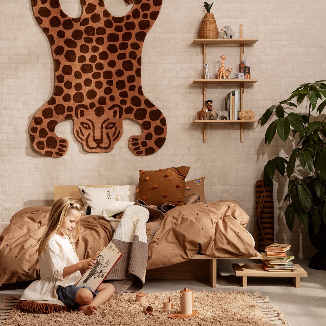 "Leopard print wall hanging with brown tones, cozy tan bedding, and earthy decor elements in a stylish bedroom setting."
