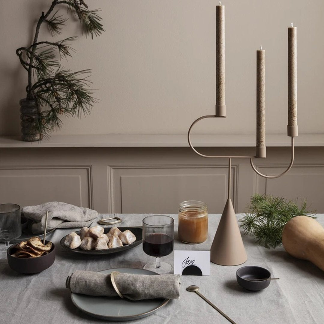 Neutral tones with beige candle holder and soft textures; elegant table setting featuring earth-toned dishes and decor.