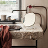 Round gold mirror on a rustic stone sink with a brown cloth and industrial metal accents in a natural light setting.