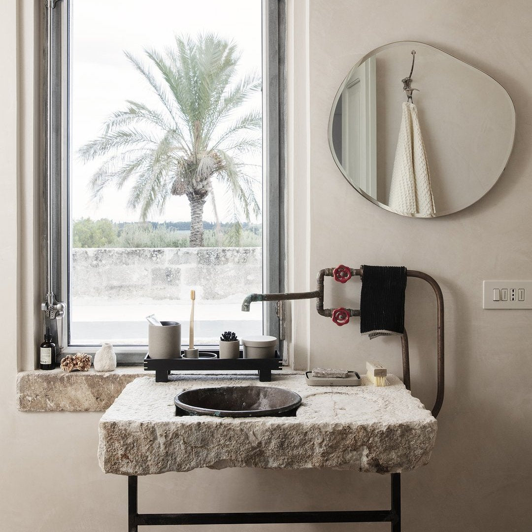 Elegant bathroom sink in natural stone with a smooth white surface and a contrasting black basin, framed by warm neutrals.