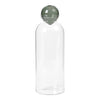 Clear glass water bottle with a round green lid. Simple, modern design enhances any decor.