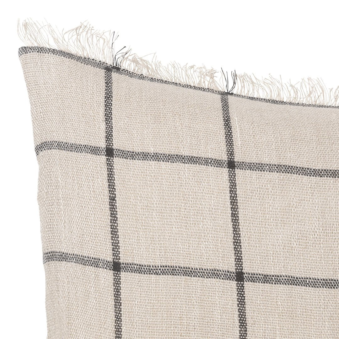 Beige fabric pillow with black grid pattern and frayed edges. Perfect for a modern, cozy decor style.