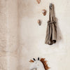 "Beige wall with textured stone, striped brown and cream hanging bag, and a soft white and brown unicorn plush toy."