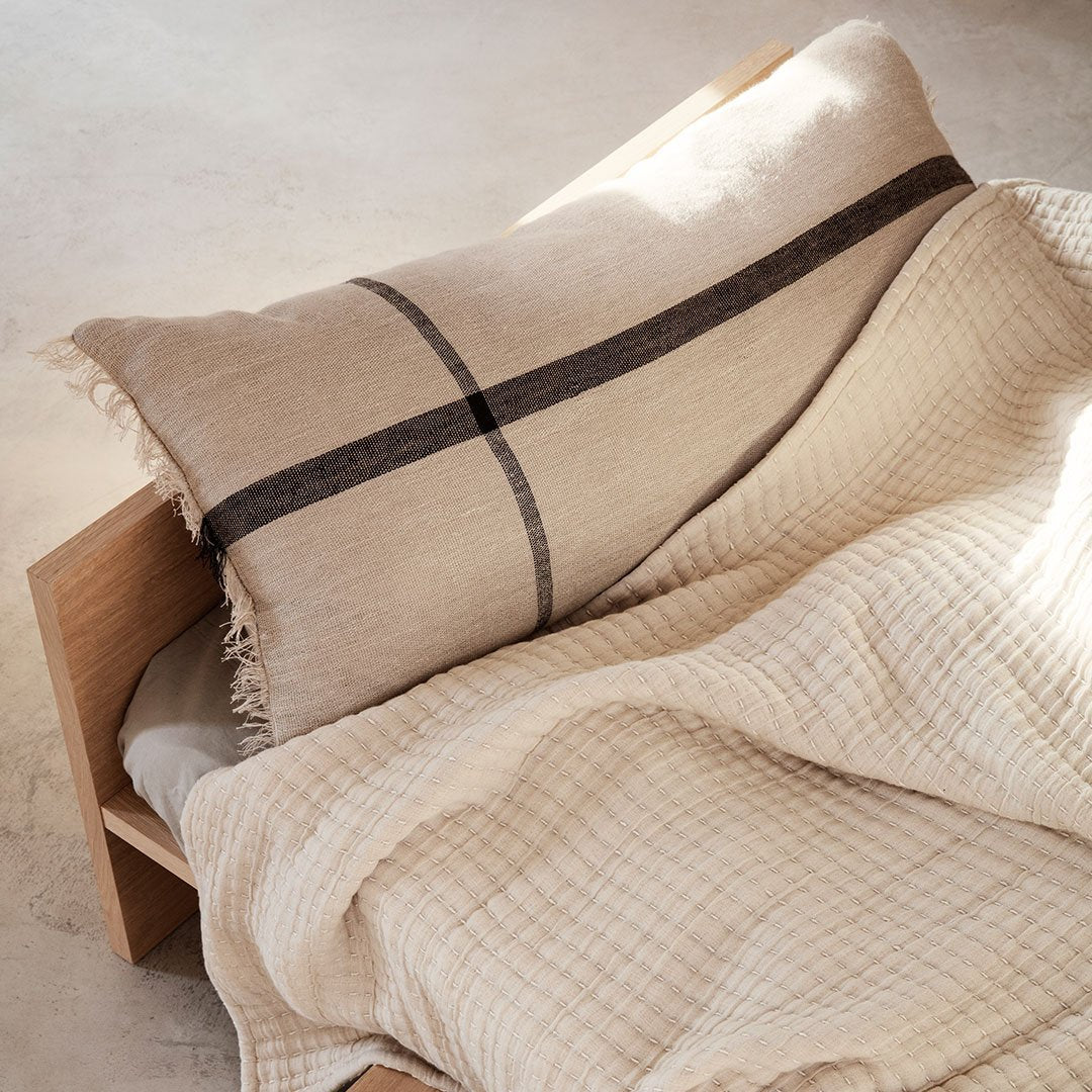 Beige textured throw blanket and pillow with a dark stripe pattern, creating a cozy and modern aesthetic.