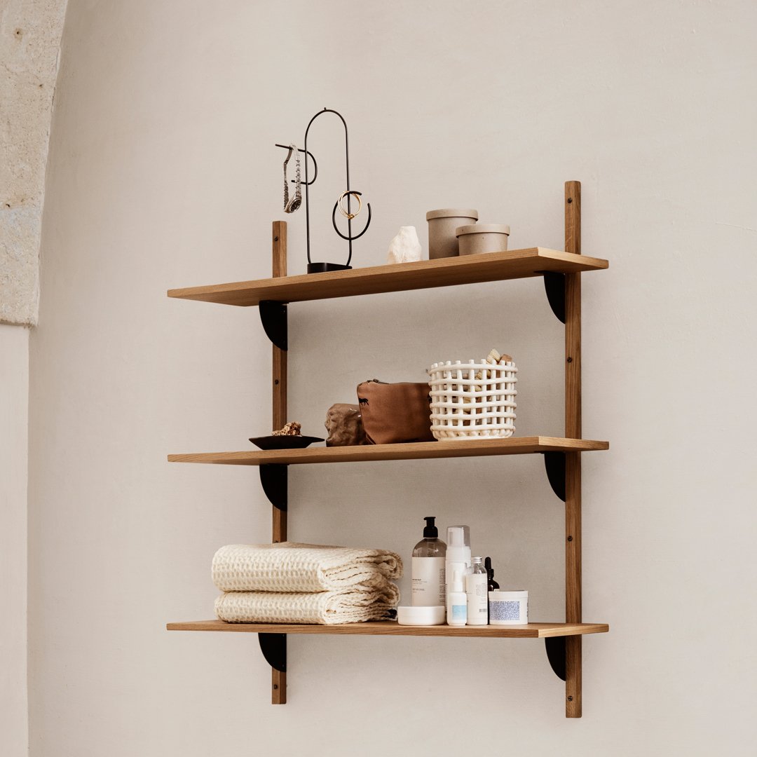 Wooden shelves with a warm brown finish, showcasing neutral tones and textured patterns of storage baskets and towels.