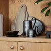 Black ceramic dishware with metallic sheen, paired with natural wood textures and soft gray elements.