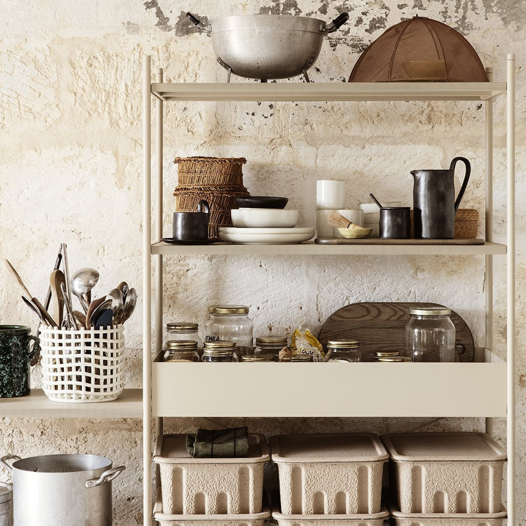 "Beige shelving unit adorned with glass jars, woven baskets, and assorted ceramic and metal kitchenware."