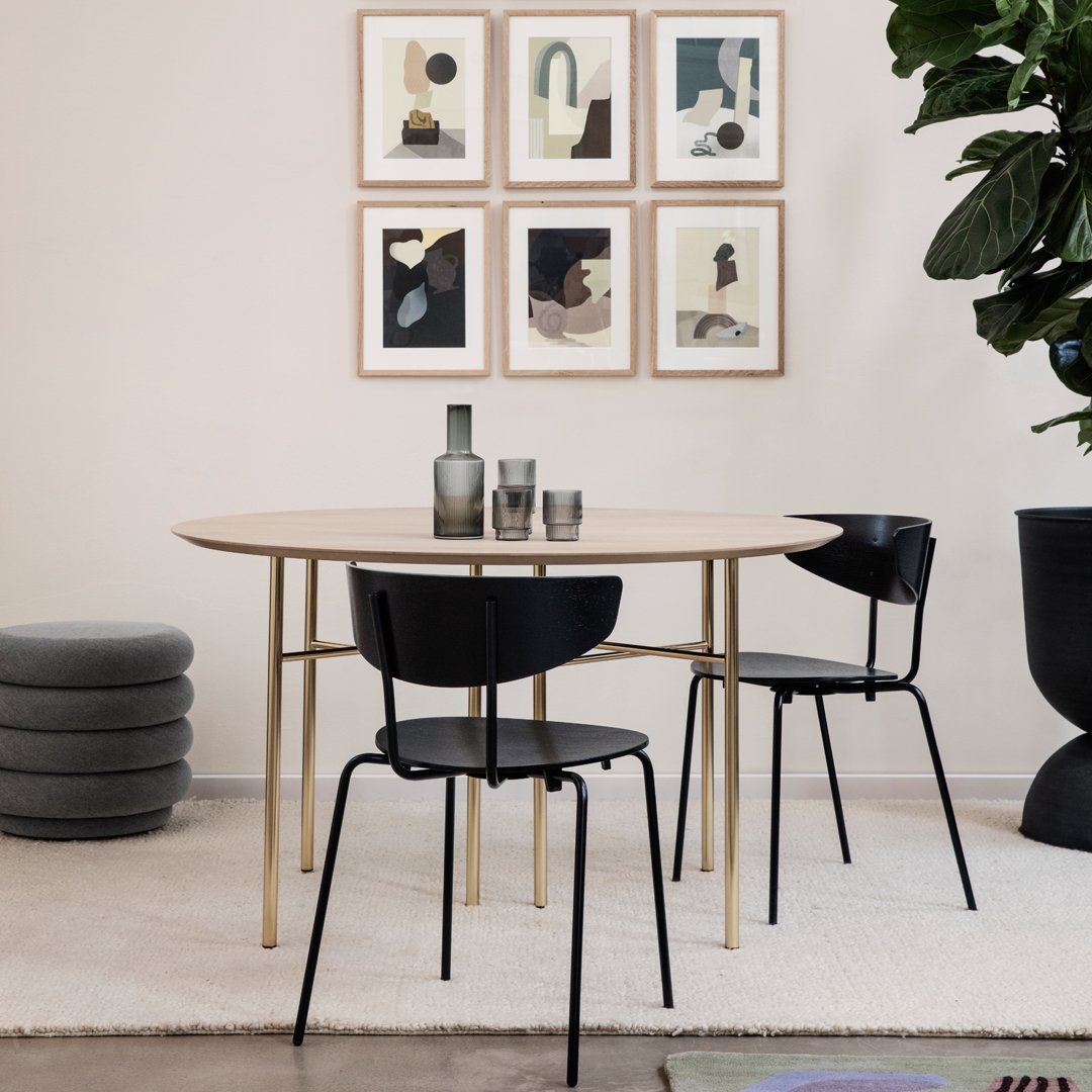 Minimalist round dining table with natural wood finish, sleek black chairs, and soft neutral decor accents.