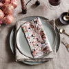"Marble-patterned napkin in soft pink, green, and black on textured linen with pastel plates."