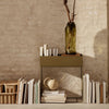 Green and beige storage table with a sleek design, paired with a textured vase and stacked books against a neutral backdrop.