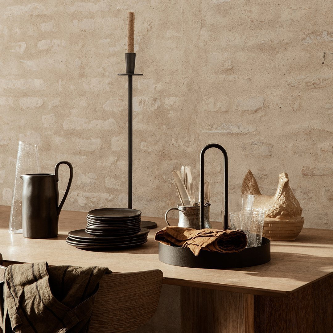 "Minimalist black tableware with natural textures, warm tones, and earthy accents against a rustic beige background."