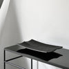 Black rectangular serving platter with a smooth, matte finish displayed on a sleek black surface.