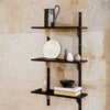 Black shelving unit with sleek lines and neutral decor against textured beige wall.
