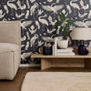 Navy blue wallpaper with white crane and bird patterns, complemented by neutral furniture and warm wood tones.