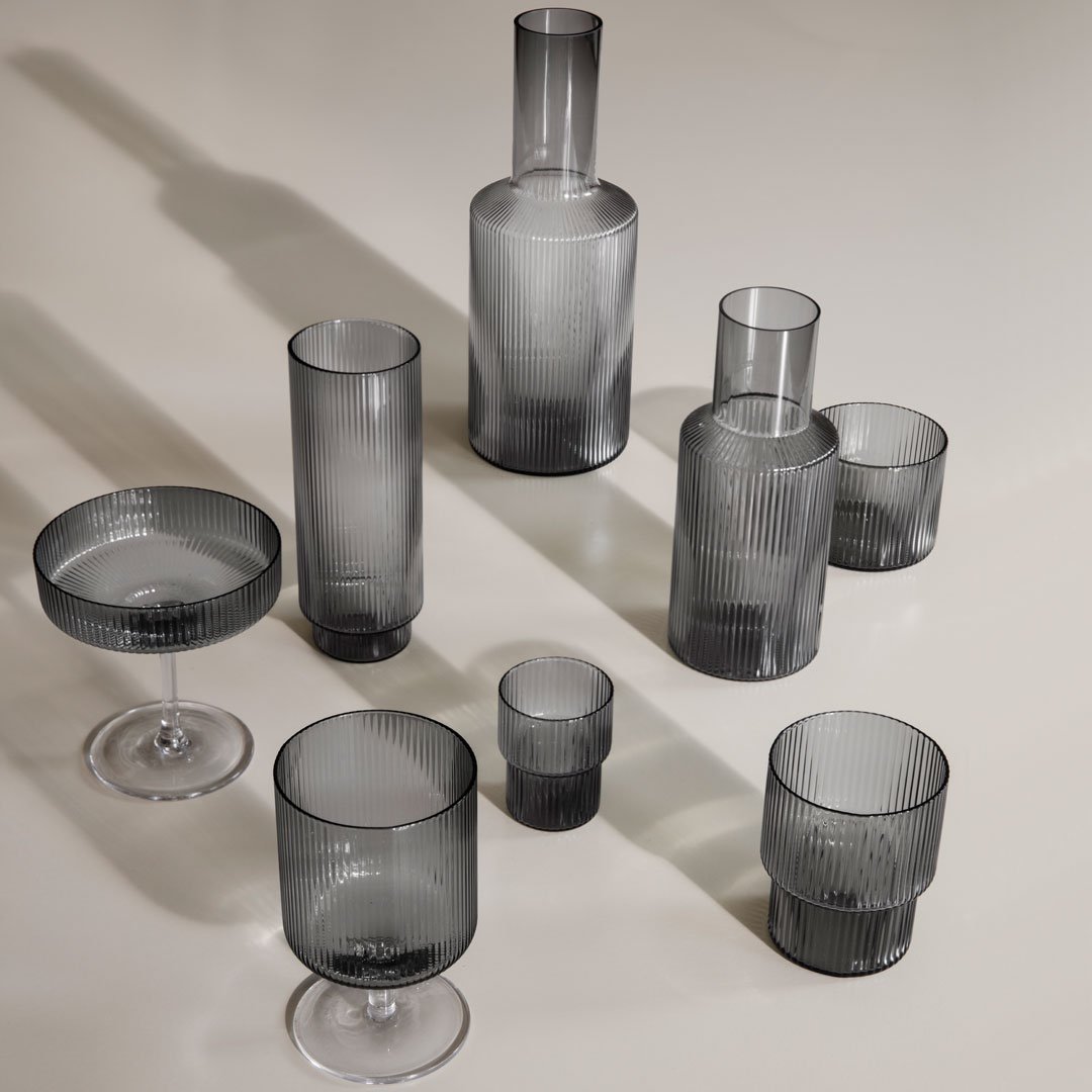 Elegant grey glassware set featuring various shapes and subtle striped patterns, perfect for modern dining.