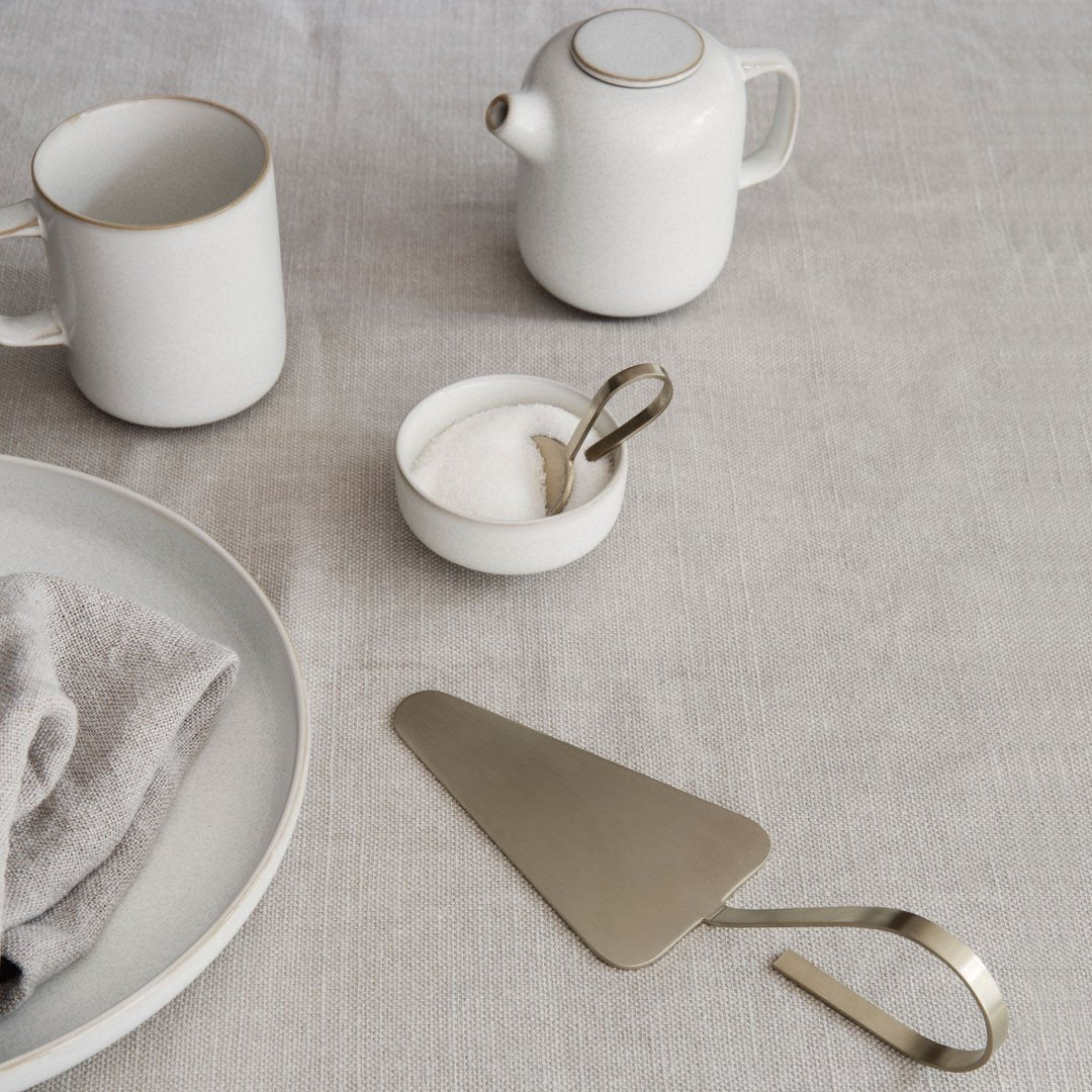 White ceramics with gold accents on a neutral linen backdrop, featuring minimalist design and subtle textures.