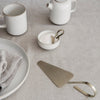 Elegant white ceramics and brushed brass accents on a neutral linen backdrop, showcasing a minimalist aesthetic.