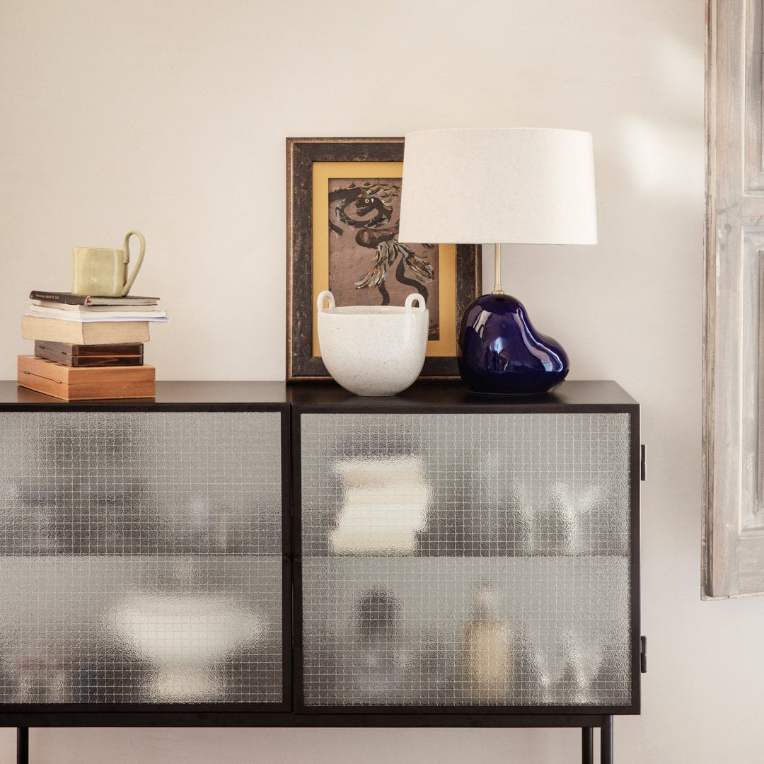 Modern black cabinet with frosted glass doors, featuring white, blue, and earthy tones in decor accents.