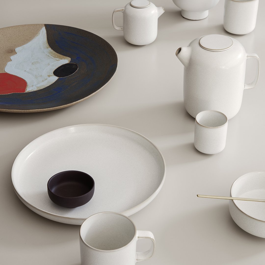 Elegant porcelain tableware featuring white, navy, and earthy tones with abstract patterns and smooth finishes.