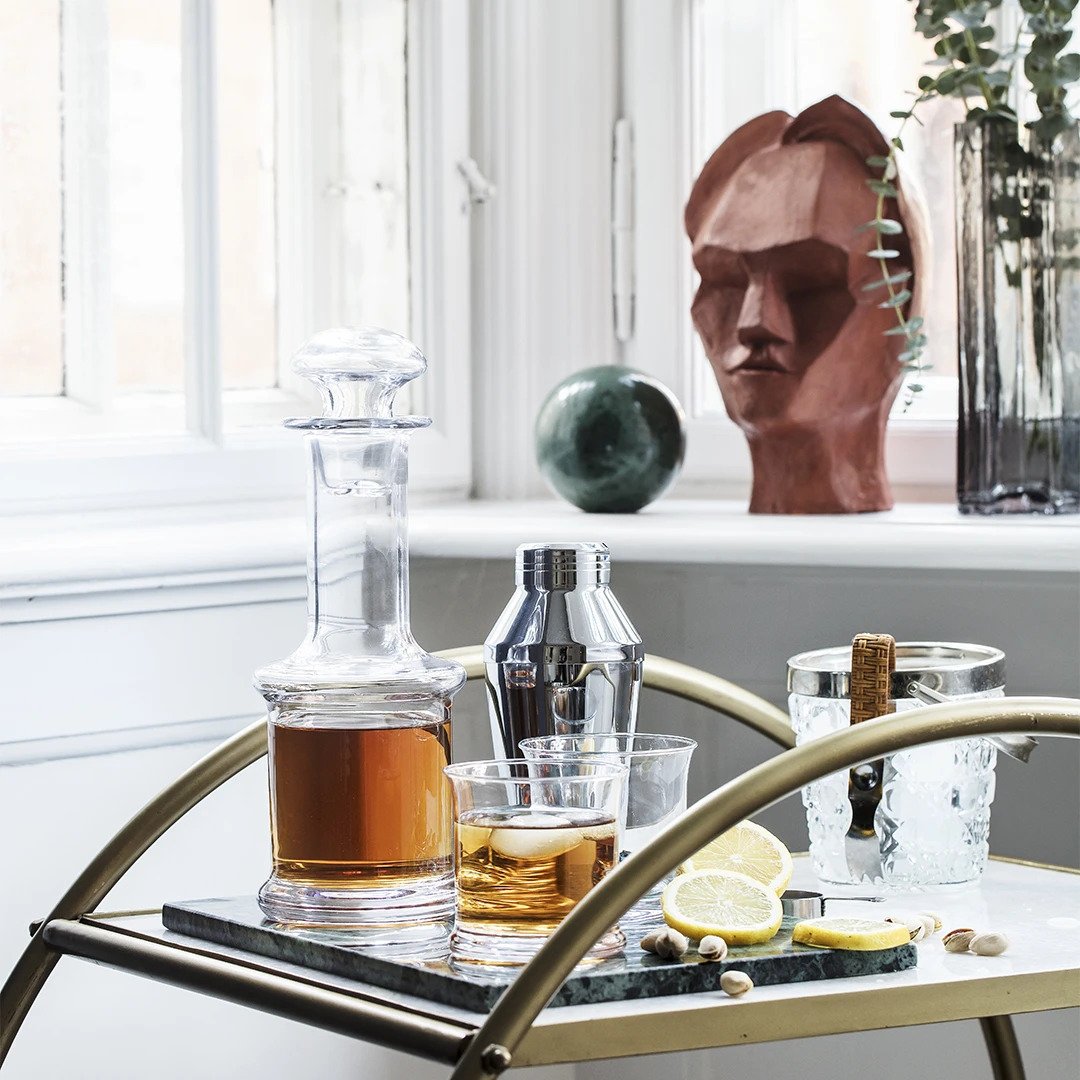 Elegant glassware and a ceramic statue with earthy tones, featuring clear and smoky textures. Modern tabletop decor.
