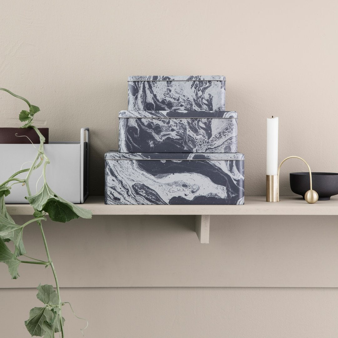 Stacked gray and white marbled storage boxes on a shelf, complemented by minimalistic decor.