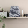 Stacked gray and white marbled storage boxes on a shelf, complemented by minimalistic decor.