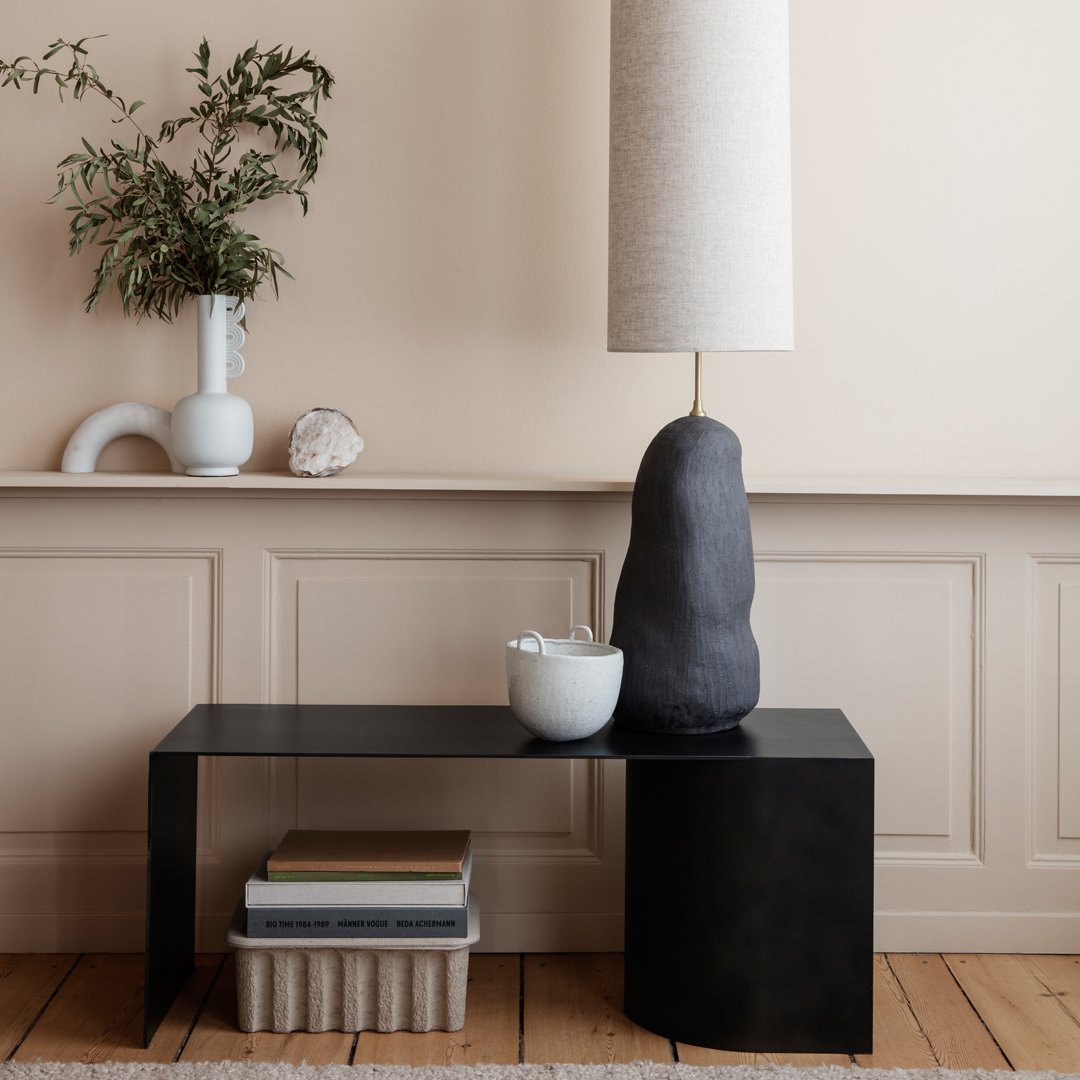 Modern black console table with a smooth finish, complemented by neutral tones and organic shapes in decor.