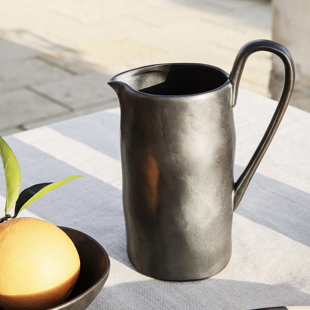 Sleek black ceramic pitcher with a textured finish, perfect for modern table settings.