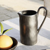 Sleek black ceramic pitcher with a textured finish, perfect for modern table settings.